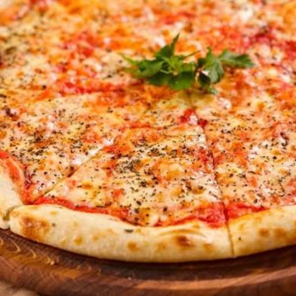 A whole, sliced Margherita pizza with basil on a wooden serving board.